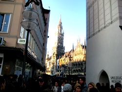 A crowd filling a Munich street below the towers of the Neues Rathaus