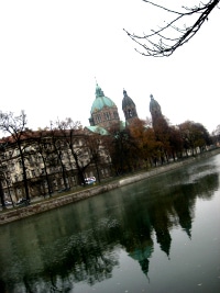 The Isar in Munich, bare trees along the bank and a domed tower reflected in the water