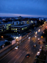 Traffic on a Budapest boulevard seen from above, headlights streaking in the blue hour